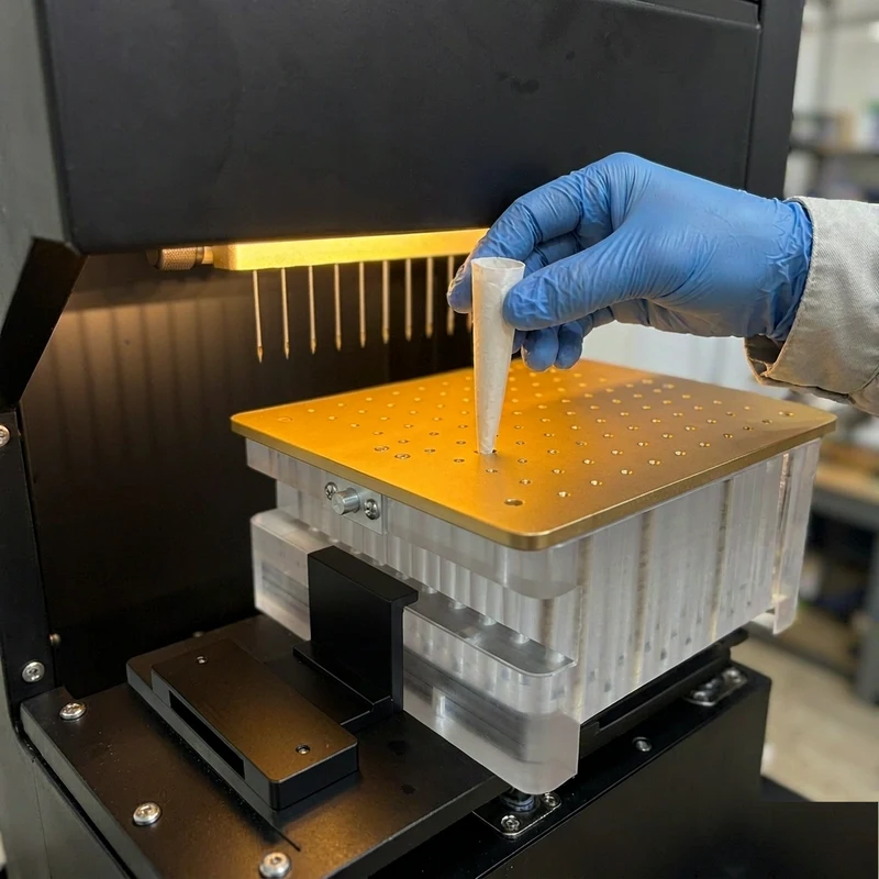 Operator lifting a filled pre-roll cone from the machine tray for a sample weight check